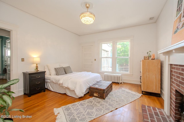1211 Everett Ave, Louisville, KY 40204 - bedroom featuring radiator heating unit, a fireplace, wood finished floors, and a chandelier