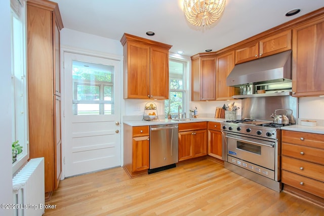 1211 Everett Ave, Louisville, KY 40204 - kitchen with appliances with stainless steel finishes, under cabinet range hood, radiator, light countertops, and light wood finished floors