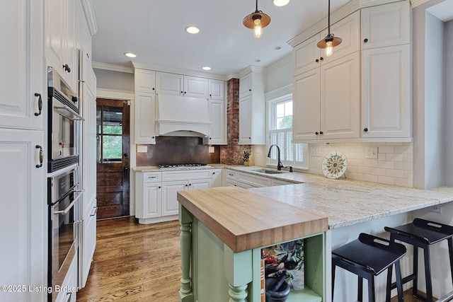 1700 Shady Ln, Louisville, KY 40205 - kitchen with butcher block countertops, appliances with stainless steel finishes, white cabinets, custom range hood, and ornamental molding