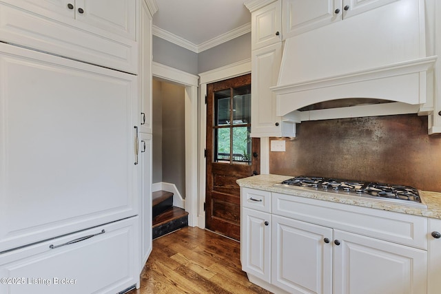 1700 Shady Ln, Louisville, KY 40205 - kitchen with custom range hood, stainless steel gas stovetop, light wood-style flooring, ornamental molding, and white cabinetry