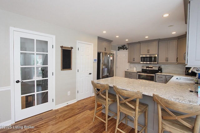 4201 Patterson Park Ct, Louisville, KY 40299 - kitchen featuring stainless steel appliances, gray cabinets, a peninsula, light stone counters, and light wood-style floors