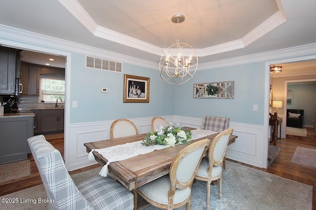 4201 Patterson Park Ct, Louisville, KY 40299 - dining space featuring a chandelier, a raised ceiling, crown molding, a wainscoted wall, and dark wood-style floors