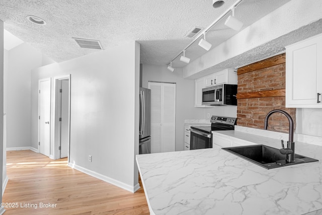1128 Cherokee Rd Apt 1A, Louisville, KY 40204 - kitchen featuring stainless steel appliances, light wood finished floors, white cabinets, rail lighting, and a textured ceiling