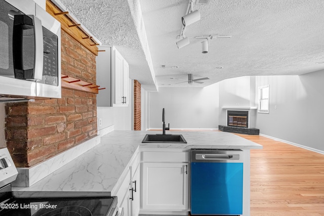 1128 Cherokee Rd Apt 1A, Louisville, KY 40204 - kitchen with stainless steel appliances, a peninsula, a glass covered fireplace, a textured ceiling, and white cabinets