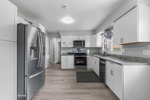 6206 Tabor Dr, Louisville, KY 40218 - kitchen with appliances with stainless steel finishes, white cabinetry, light wood finished floors, and light stone counters