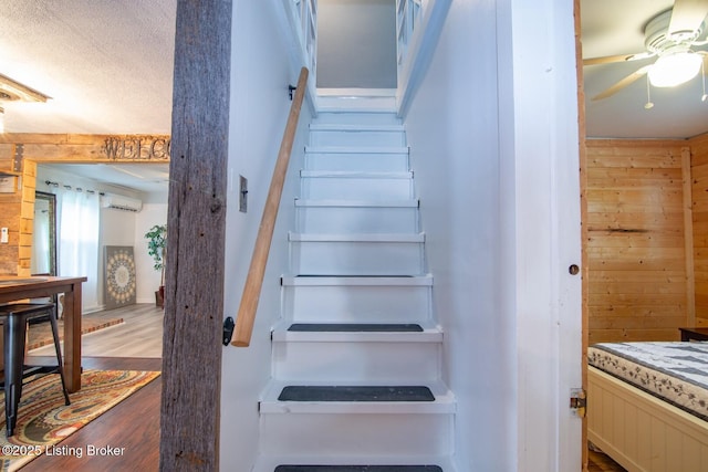 650 Midway Rd, Guston, KY 40142 - staircase featuring wood walls, a wall mounted AC, a ceiling fan, wood finished floors, and a textured ceiling