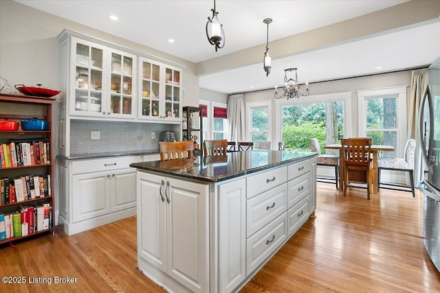 2449 Ransdell Ave, Louisville, KY 40204 - kitchen featuring backsplash, light wood-style floors, hanging light fixtures, white cabinetry, and a kitchen island