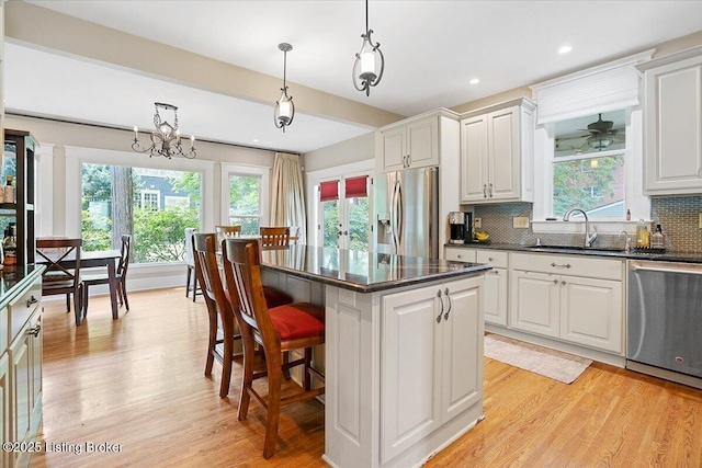 2449 Ransdell Ave, Louisville, KY 40204 - kitchen featuring stainless steel appliances, backsplash, a center island, light wood-style floors, and hanging light fixtures