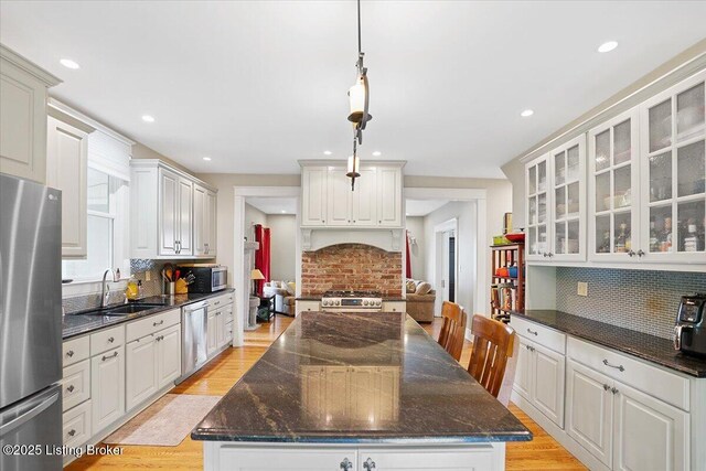 2449 Ransdell Ave, Louisville, KY 40204 - kitchen with stainless steel appliances, backsplash, glass insert cabinets, light wood-style flooring, and recessed lighting