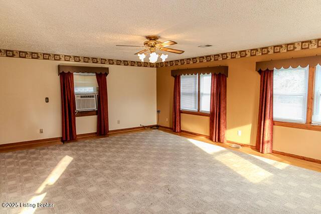 4883 S Reeves Rd, Scottsburg, IN 47170 - carpeted spare room featuring a textured ceiling, a ceiling fan, healthy amount of natural light, and cooling unit