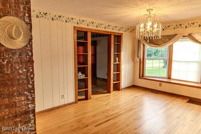 4883 S Reeves Rd, Scottsburg, IN 47170 - unfurnished room featuring wood finished floors, a chandelier, and wood walls