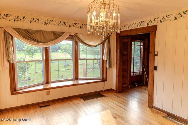 4883 S Reeves Rd, Scottsburg, IN 47170 - unfurnished dining area with light wood-type flooring, a chandelier, and plenty of natural light