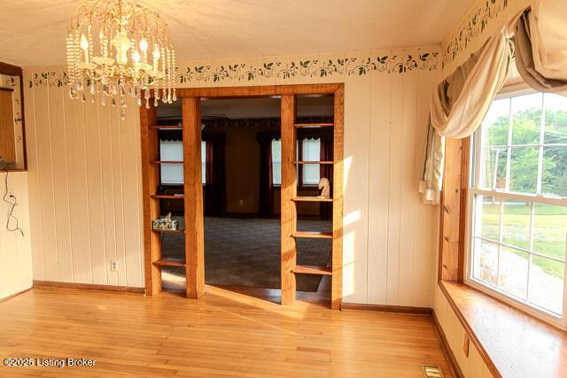 4883 S Reeves Rd, Scottsburg, IN 47170 - spare room with light wood-style floors, a chandelier, and wooden walls