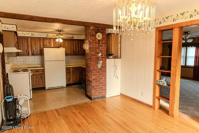 4883 S Reeves Rd, Scottsburg, IN 47170 - kitchen featuring white appliances, a ceiling fan, under cabinet range hood, light wood-style flooring, and a chandelier