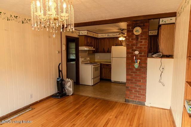 4883 S Reeves Rd, Scottsburg, IN 47170 - kitchen featuring white appliances, under cabinet range hood, a ceiling fan, light wood-type flooring, and a chandelier