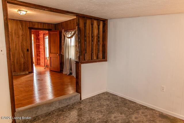 4883 S Reeves Rd, Scottsburg, IN 47170 - spare room featuring wood walls, a textured ceiling, carpet, wood finished floors, and beamed ceiling