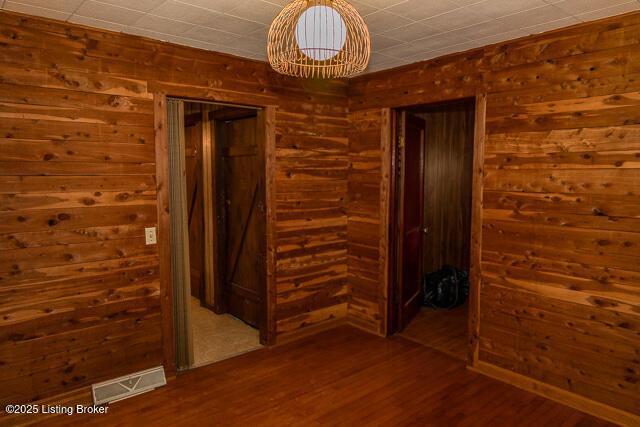 4883 S Reeves Rd, Scottsburg, IN 47170 - empty room with wood finished floors, wood walls, and a chandelier