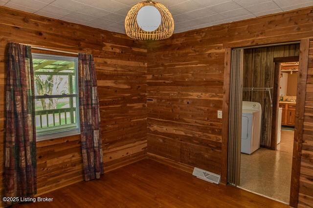 4883 S Reeves Rd, Scottsburg, IN 47170 - spare room featuring washer / clothes dryer, wood walls, and wood finished floors