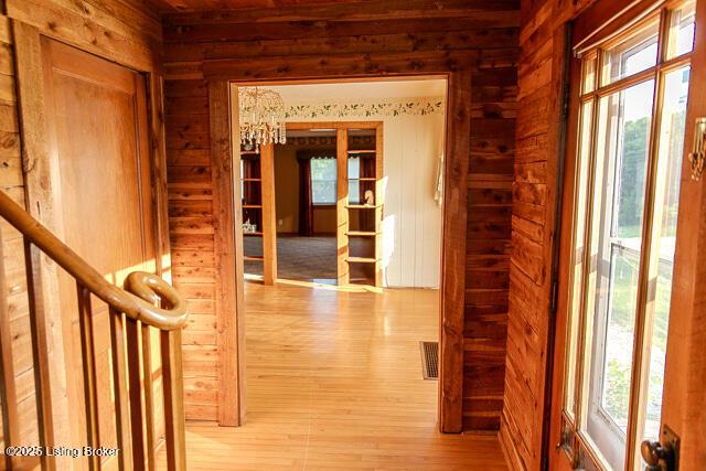 4883 S Reeves Rd, Scottsburg, IN 47170 - hall featuring wooden walls, plenty of natural light, wood finished floors, and a chandelier