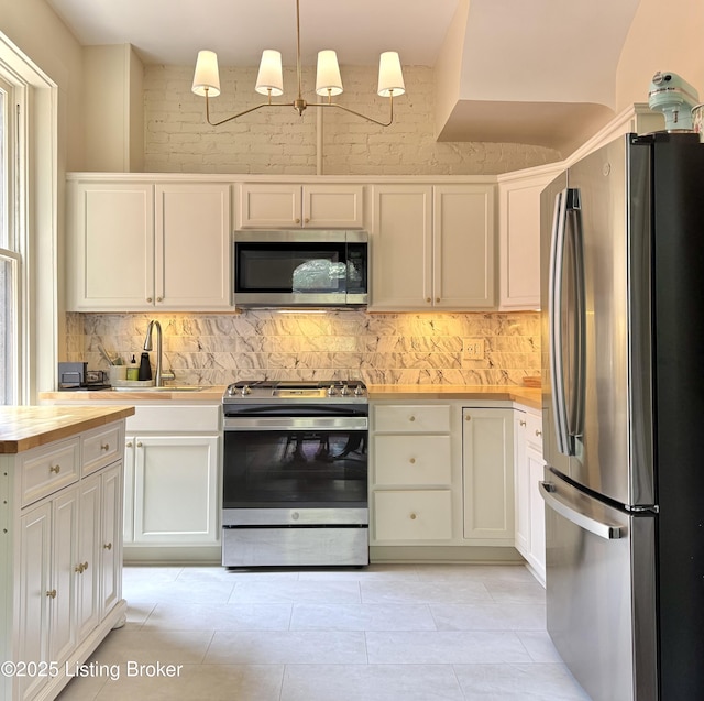 416 Belgravia Ct, Louisville, KY 40208 - kitchen featuring appliances with stainless steel finishes, backsplash, white cabinetry, and wooden counters