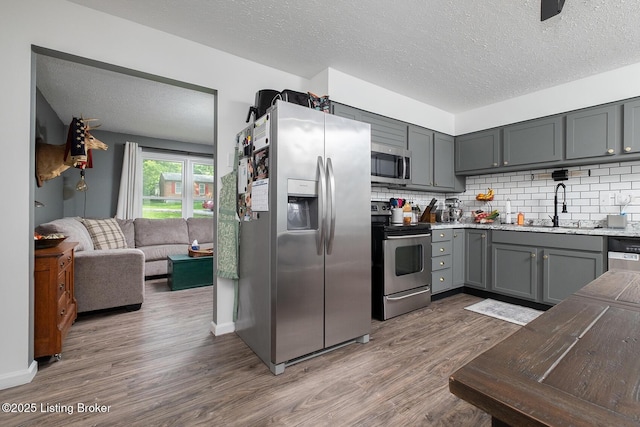1008 E Mailback Way, Crestwood, KY 40014 - kitchen with appliances with stainless steel finishes, wood finished floors, a textured ceiling, gray cabinets, and tasteful backsplash