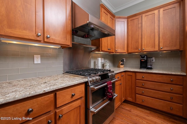 9508 Norton Commons Blvd Unit 102, Prospect, KY 40059 - kitchen featuring wall chimney exhaust hood, range with two ovens, backsplash, brown cabinets, and light wood-style floors