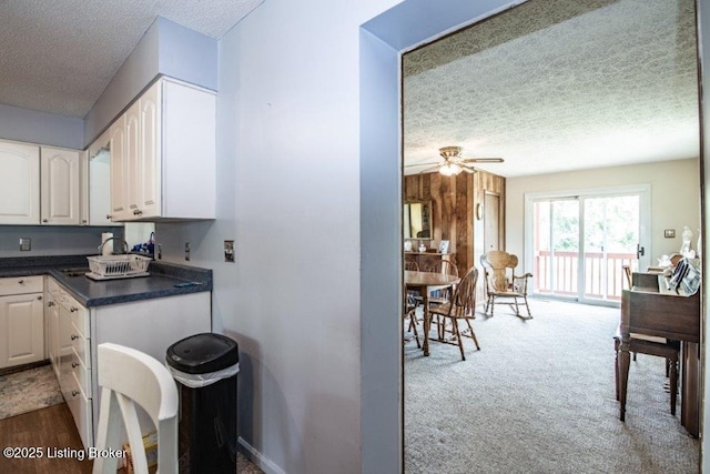 825 Crocus Dr, Radcliff, KY 40160 - kitchen featuring a textured ceiling, white cabinets, dark countertops, a ceiling fan, and carpet floors