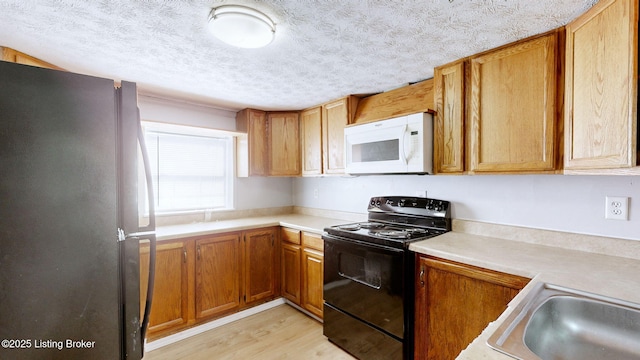 1117 6th St, Carrollton, KY 41008 - kitchen featuring freestanding refrigerator, white microwave, black electric range oven, light wood-style floors, and light countertops