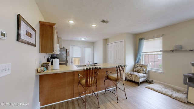 7236 Michael Benjamin Cir, Crestwood, KY 40014 - kitchen with light wood-style floors, freestanding refrigerator, a peninsula, brown cabinets, and light countertops
