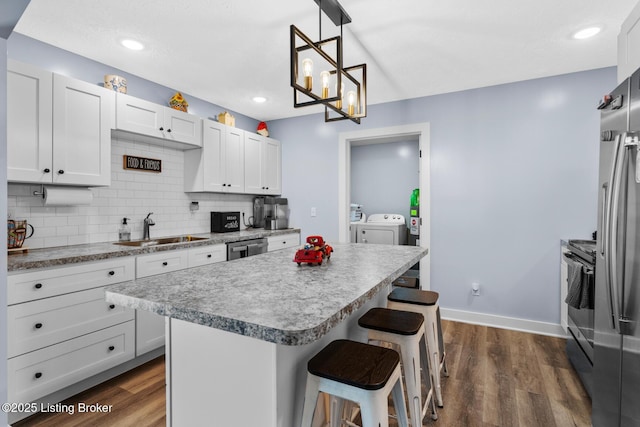 63 Davis Norton Ln, Harned, KY 40144 - kitchen with washing machine and dryer, a kitchen breakfast bar, dark wood-type flooring, stainless steel appliances, and backsplash