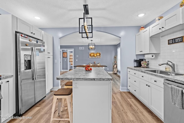 63 Davis Norton Ln, Harned, KY 40144 - kitchen featuring stainless steel appliances, arched walkways, a textured ceiling, a center island, and tasteful backsplash