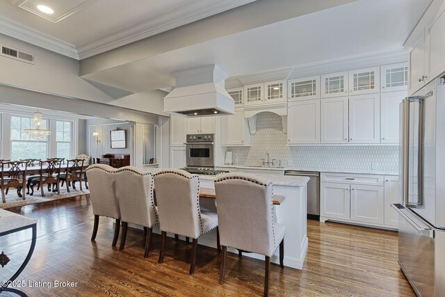 1416 Willow Ave Unit 3B, Louisville, KY 40204 - kitchen with appliances with stainless steel finishes, custom range hood, a kitchen island, a breakfast bar, and white cabinetry