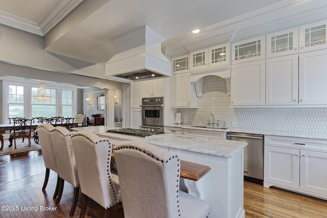 1416 Willow Ave Unit 3B, Louisville, KY 40204 - kitchen featuring stainless steel appliances, ornamental molding, a kitchen breakfast bar, wood finished floors, and custom exhaust hood