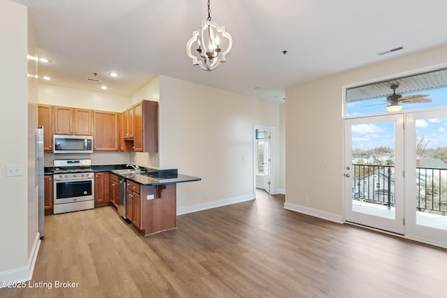 2011 Frankfort Ave Unit Unit312, Louisville, KY 40206 - kitchen featuring appliances with stainless steel finishes, light wood-style flooring, dark countertops, a chandelier, and a peninsula