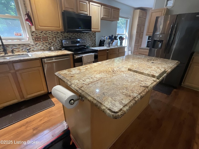 40 Sunflower Ln, Brandenburg, KY 40108 - kitchen with appliances with stainless steel finishes, light wood finished floors, a kitchen island, decorative backsplash, and light stone countertops
