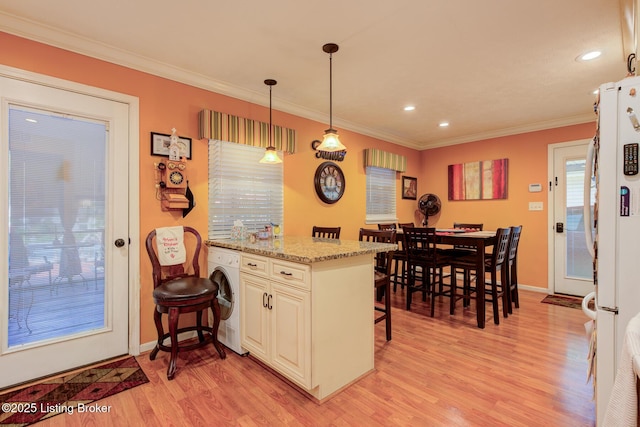 3308 Mcadams Ct, Jeffersontown, KY 40299 - kitchen with a breakfast bar area, light wood-style flooring, ornamental molding, washer / clothes dryer, and freestanding refrigerator