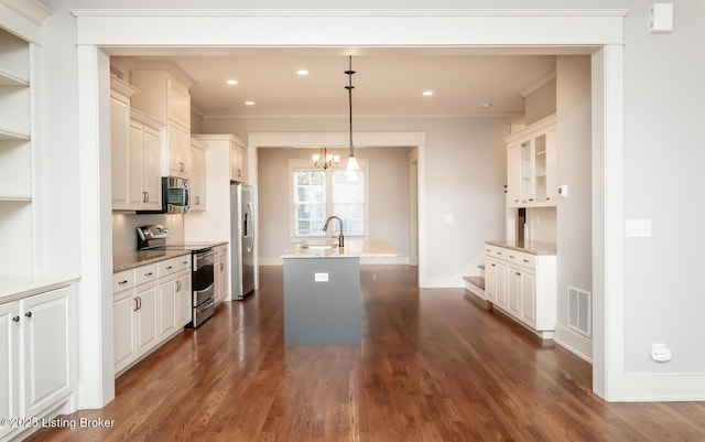 9403 Delphinium St Unit 101, Prospect, KY 40059 - kitchen featuring appliances with stainless steel finishes, a center island with sink, crown molding, dark wood-type flooring, and light stone counters