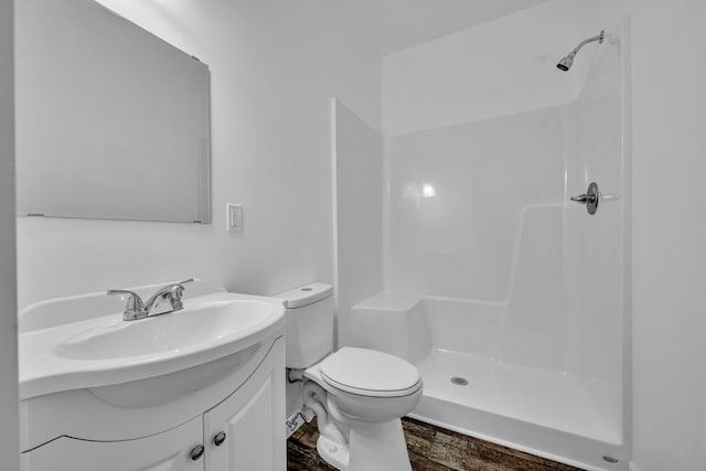 bathroom featuring wood finished floors, a stall shower, vanity, and toilet