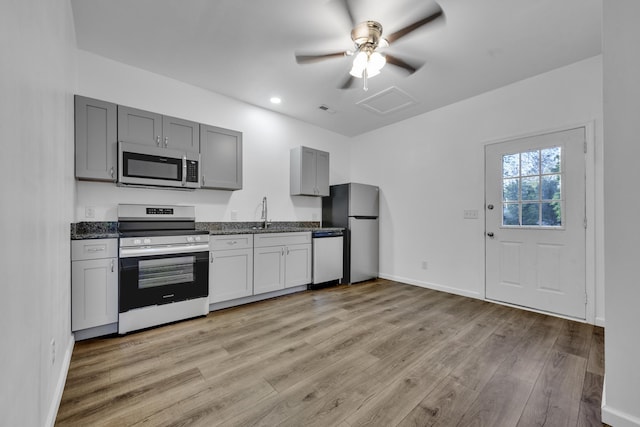 kitchen featuring light wood finished floors, stainless steel appliances, visible vents, gray cabinetry, and baseboards