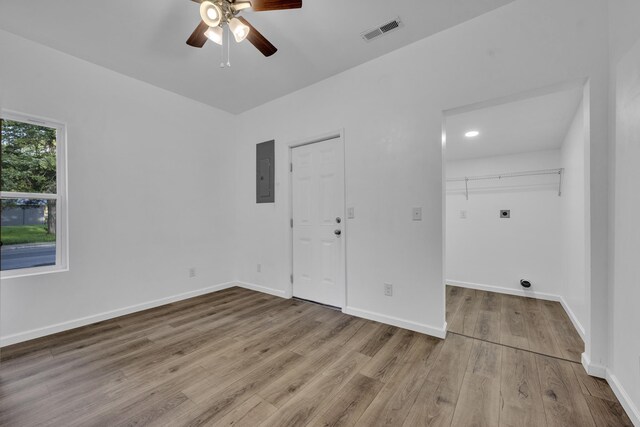 empty room featuring baseboards, wood finished floors, visible vents, and electric panel