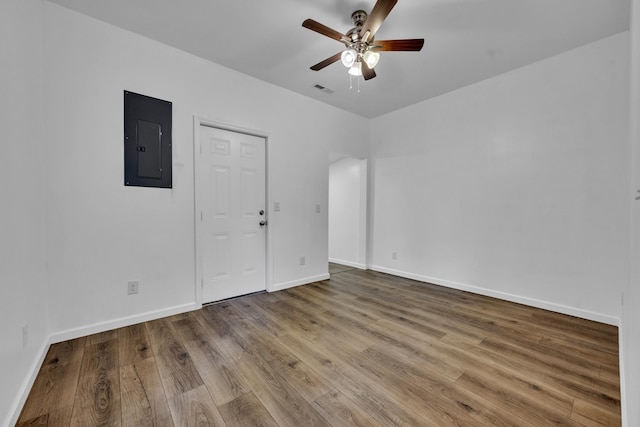 unfurnished room featuring electric panel, baseboards, visible vents, ceiling fan, and wood finished floors