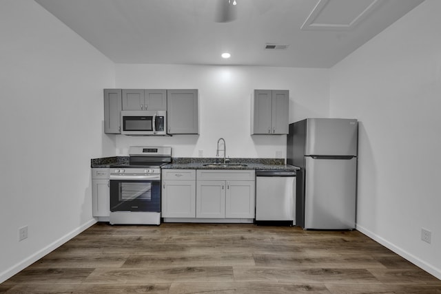 kitchen featuring appliances with stainless steel finishes, dark wood-style flooring, a sink, and baseboards