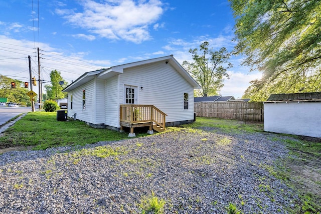 rear view of house featuring central AC unit, fence, a storage unit, a yard, and an outdoor structure