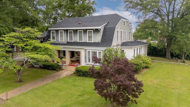 - dutch colonial featuring a front yard, a gambrel roof, a porch, and a shingled roof
