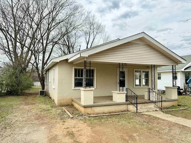 bungalow-style home with covered porch, central AC, and stucco siding