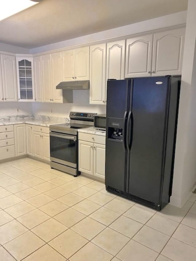 kitchen featuring electric range, light tile patterned flooring, black fridge, and white cabinets