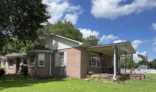 - view of property exterior with covered porch, a lawn, and brick siding