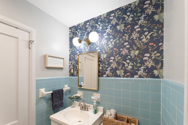  - half bath with wallpapered walls, wainscoting, vanity, and tile walls