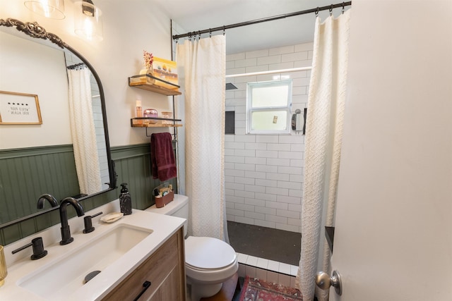  - bathroom featuring a stall shower, vanity, and a wainscoted wall