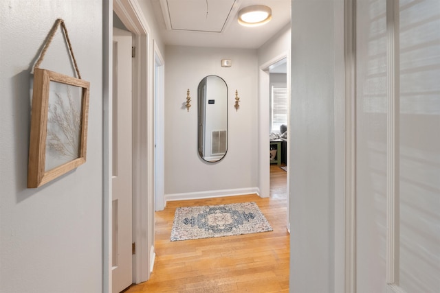  - hall featuring attic access and wood finished floors